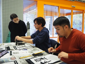 Students focusing on calligraphy under the guidance of instructor Morita